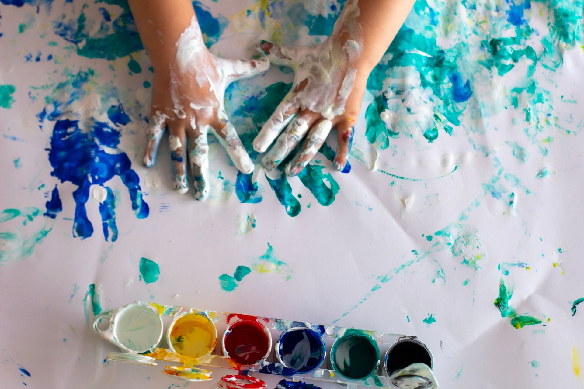 The baby draws on paper with finger paints.