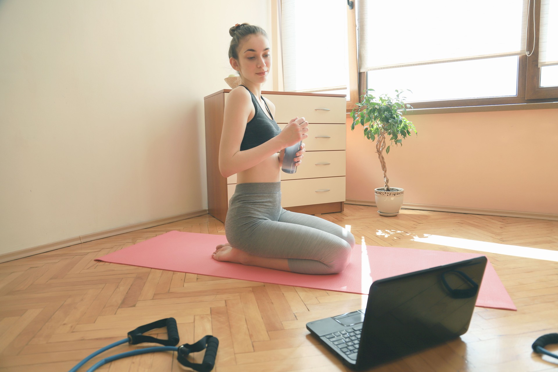 Mujer joven haciendo ejercicios en casa con la ayuda de Internet