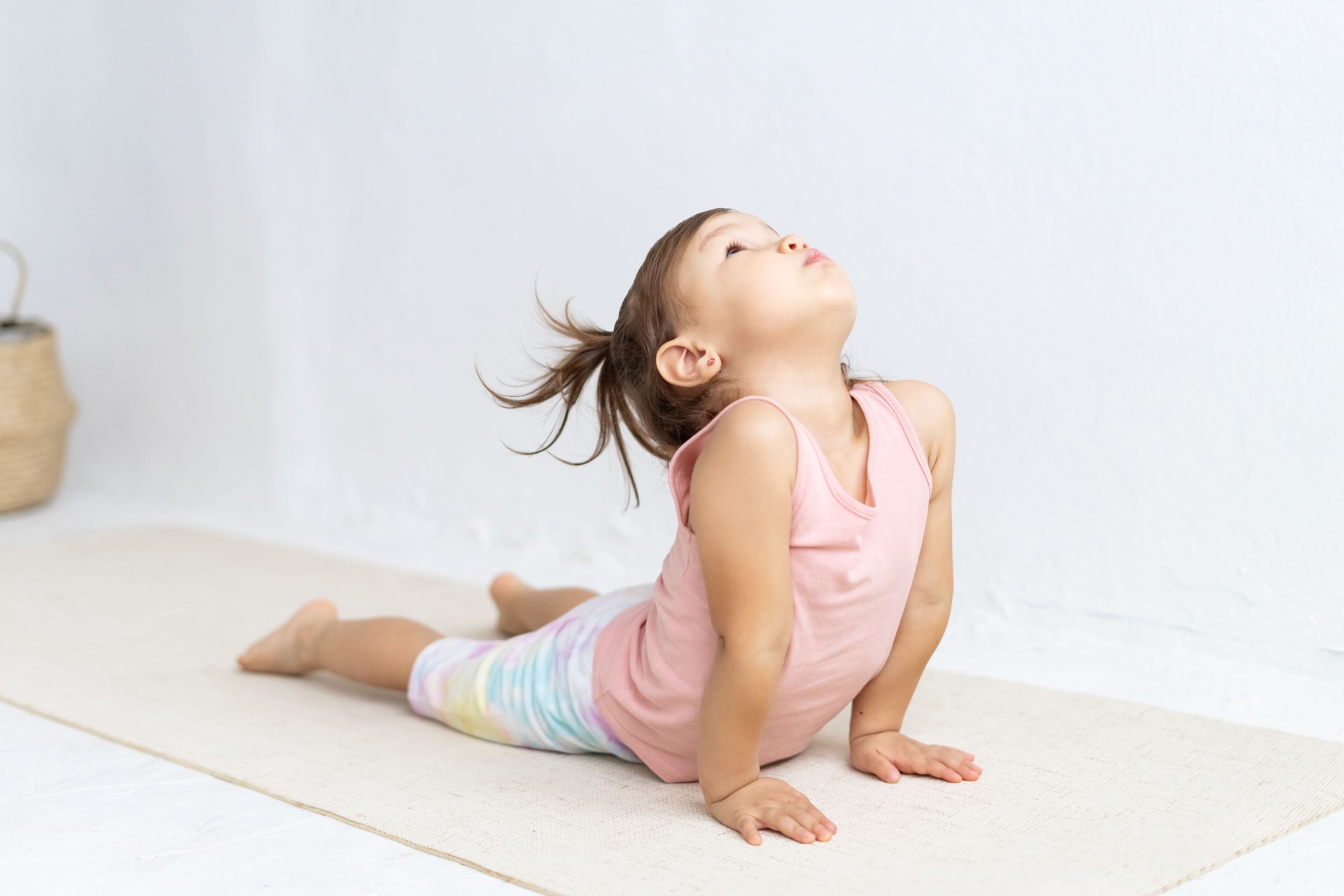 Little sporty girl practicing yoga, doing Ardha bhudjangasana exercise. Baby Cobra pose.